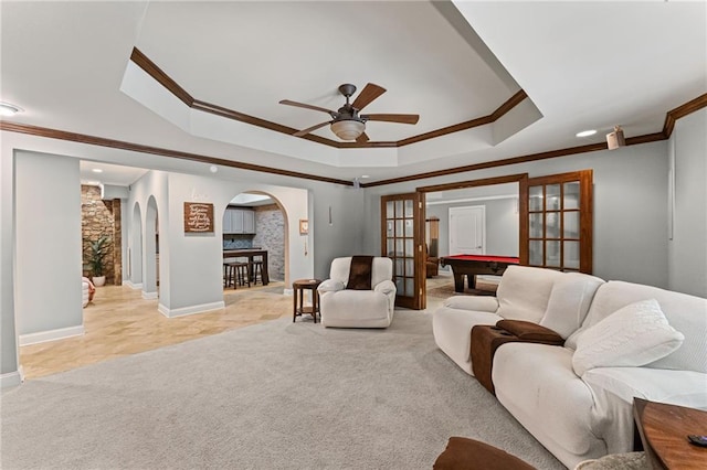 3560 Greenside Ct, Dacula, GA 30019 - living area with arched walkways, ornamental molding, a tray ceiling, a ceiling fan, and light colored carpet