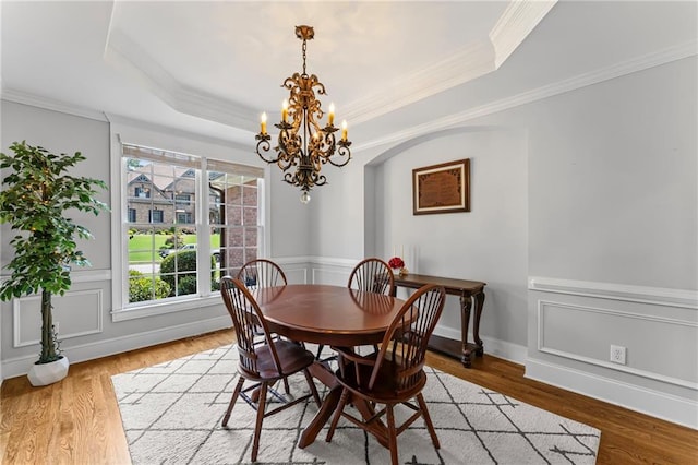 3560 Greenside Ct, Dacula, GA 30019 - dining space with a chandelier, a tray ceiling, wood finished floors, arched walkways, and ornamental molding