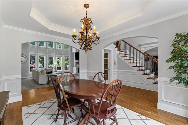 3560 Greenside Ct, Dacula, GA 30019 - dining space featuring arched walkways, a chandelier, light wood-style flooring, stairway, and a raised ceiling