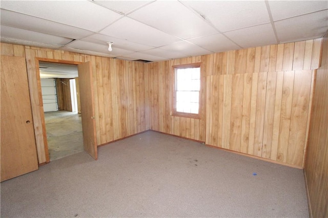 unfurnished room featuring a drop ceiling and wood walls