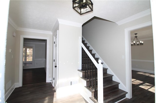 stairway with a notable chandelier, wood-type flooring, and ornamental molding