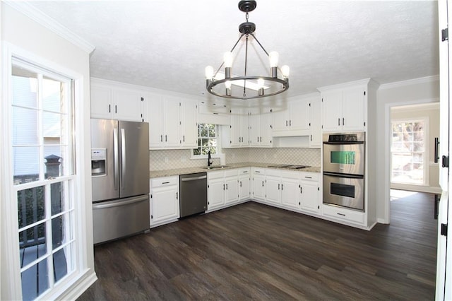 kitchen with white cabinetry, ornamental molding, appliances with stainless steel finishes, and hanging light fixtures