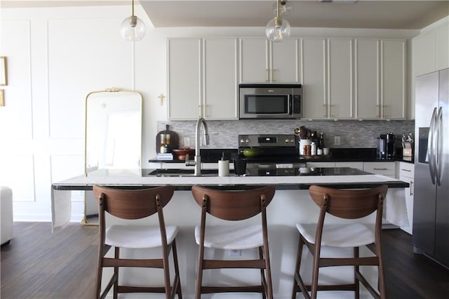 711 Cosmopolitan Dr Unit 413, Atlanta, GA 30324 - kitchen featuring appliances with stainless steel finishes, backsplash, dark countertops, and hanging light fixtures