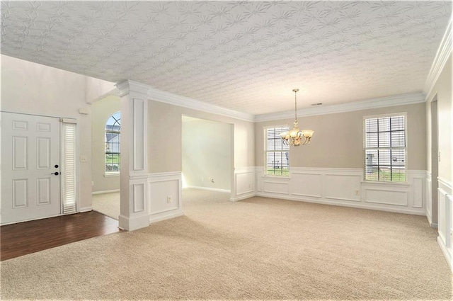 interior space with carpet floors, a chandelier, a textured ceiling, and ornamental molding