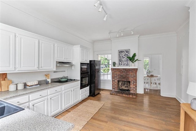 343 Josephine St NE, Atlanta, GA 30307 - kitchen with black appliances, under cabinet range hood, white cabinets, light countertops, and light wood-style flooring