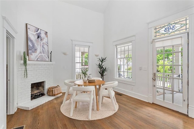 343 Josephine St NE, Atlanta, GA 30307 - dining area featuring wood finished floors, a towering ceiling, and a brick fireplace