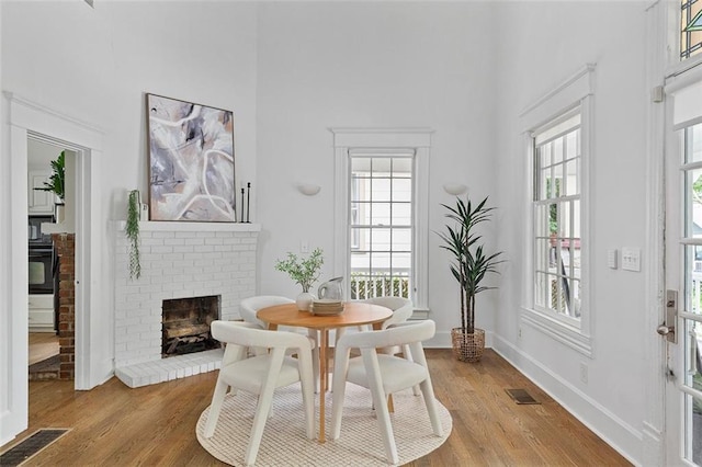 343 Josephine St NE, Atlanta, GA 30307 - dining room featuring a brick fireplace, a towering ceiling, light wood finished floors, and plenty of natural light