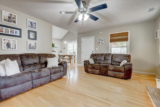 living room featuring vaulted ceiling, ceiling fan, a textured ceiling, and light hardwood / wood-style flooring