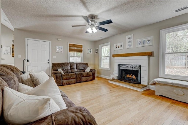 living room featuring ceiling fan, light hardwood / wood-style floors, and a textured ceiling