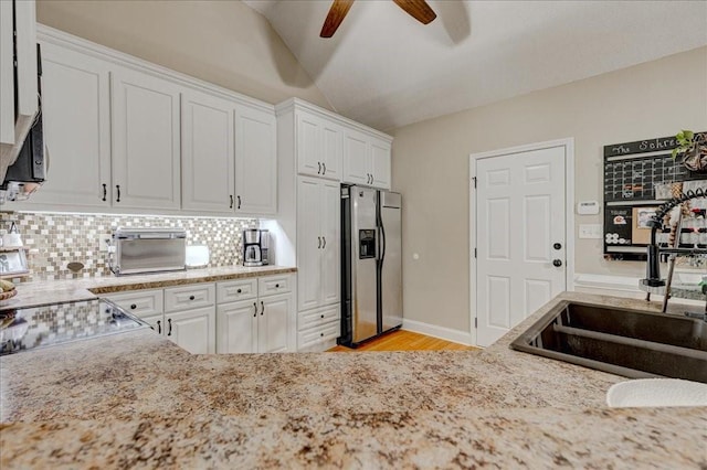 kitchen with tasteful backsplash, stainless steel refrigerator with ice dispenser, sink, and white cabinets