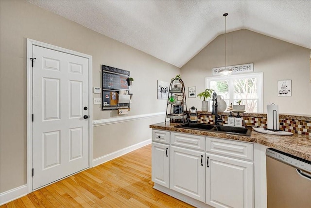 kitchen featuring decorative light fixtures, white cabinetry, sink, stainless steel dishwasher, and light hardwood / wood-style floors