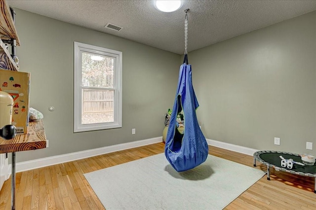 playroom with wood-type flooring and a textured ceiling