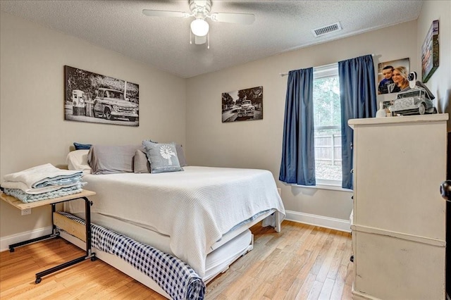 bedroom with hardwood / wood-style flooring, ceiling fan, and a textured ceiling