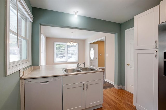 kitchen featuring sink, pendant lighting, dishwasher, light hardwood / wood-style floors, and white cabinetry