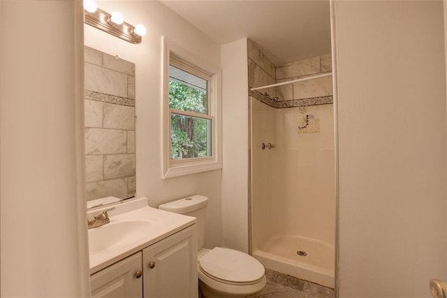 bathroom with vanity, toilet, and tiled shower