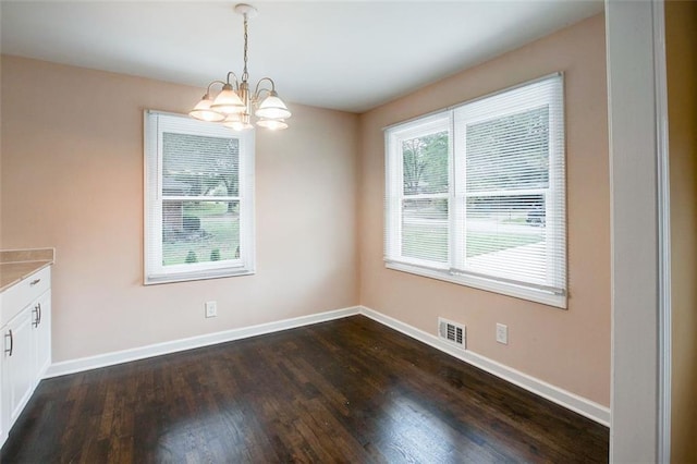 unfurnished dining area featuring dark hardwood / wood-style floors and an inviting chandelier