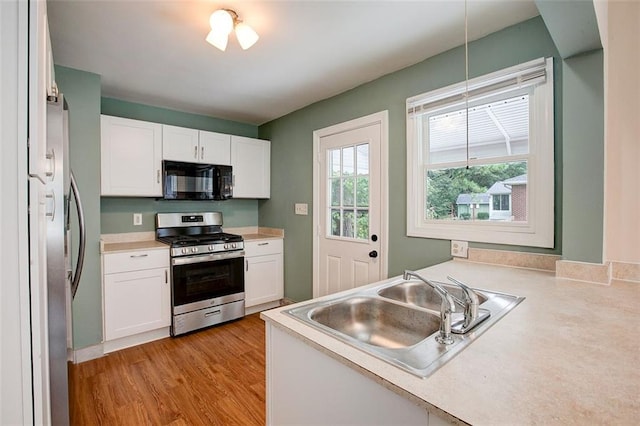 kitchen with white cabinets, light wood-type flooring, sink, and appliances with stainless steel finishes