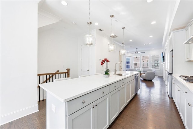 kitchen featuring pendant lighting, dark wood-type flooring, a center island with sink, sink, and white cabinetry