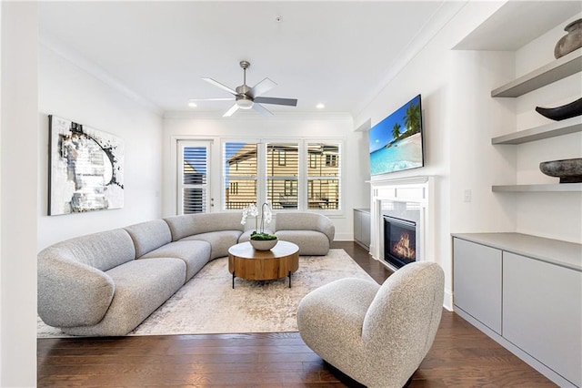 living room featuring dark hardwood / wood-style flooring, ceiling fan, and ornamental molding