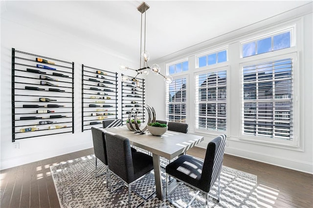 dining area featuring a notable chandelier, ornamental molding, and dark wood-type flooring