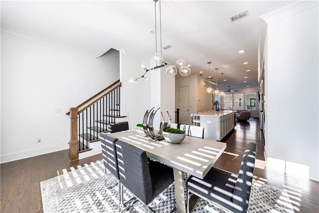 dining space with crown molding, dark wood-type flooring, and ceiling fan with notable chandelier