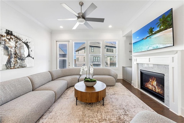 living room with a premium fireplace, crown molding, ceiling fan, and dark hardwood / wood-style floors