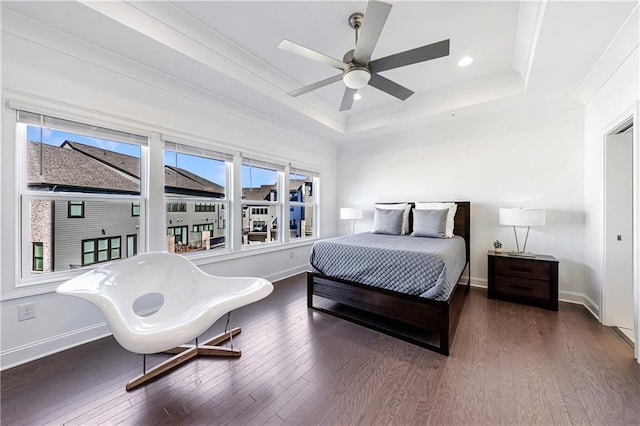 bedroom with a raised ceiling, ceiling fan, crown molding, and dark wood-type flooring