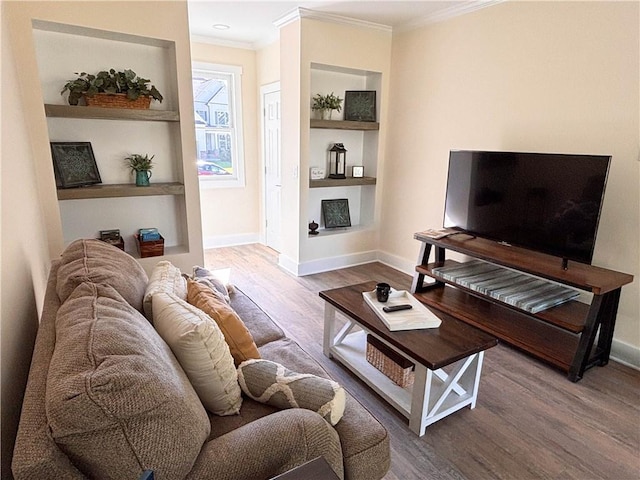 living room featuring wood-type flooring, crown molding, and built in shelves