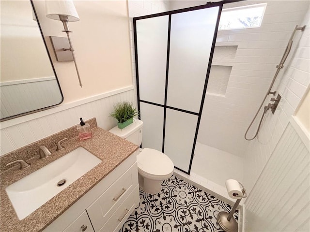 bathroom with a tile shower, vanity, tile patterned flooring, and toilet