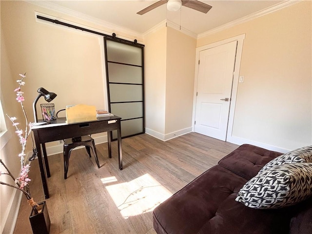 office area featuring wood-type flooring, a barn door, ornamental molding, and ceiling fan