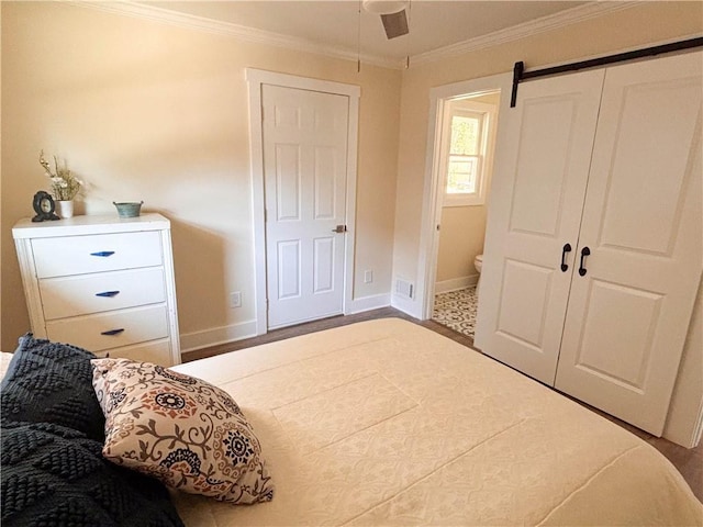 bedroom with ornamental molding, a barn door, ensuite bathroom, and ceiling fan