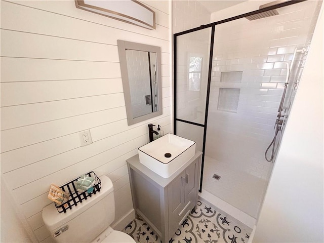 bathroom with sink, a tile shower, wooden walls, and toilet