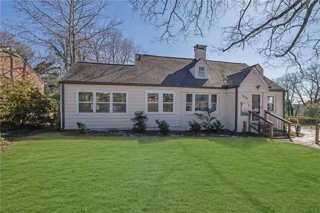 view of front facade with a front lawn, a chimney, and a shingled roof