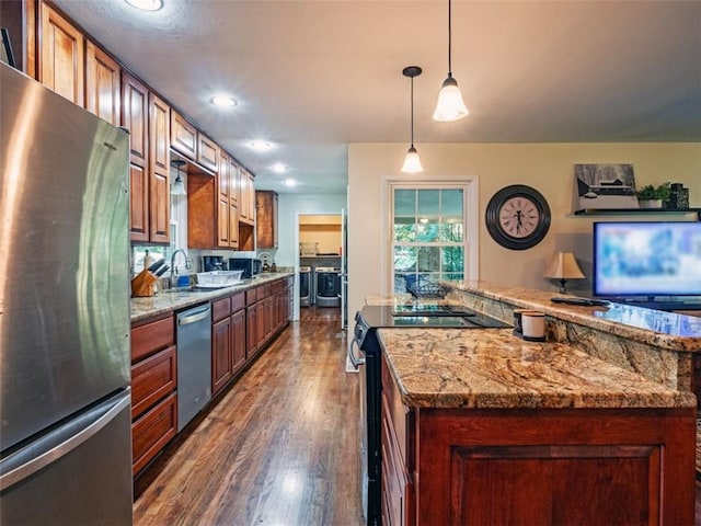 kitchen featuring light stone counters, washer and clothes dryer, stainless steel appliances, dark wood-type flooring, and a sink