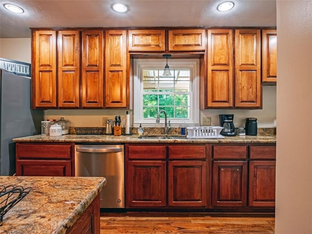 kitchen with a sink, fridge, stainless steel dishwasher, and light stone countertops