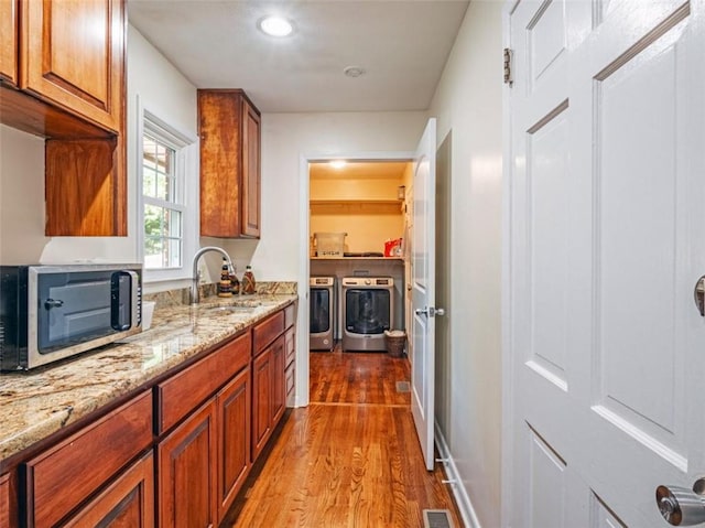 interior space featuring visible vents, wood finished floors, independent washer and dryer, light stone countertops, and a sink