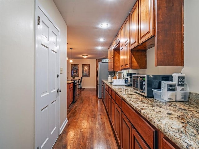 kitchen featuring light stone counters, recessed lighting, stainless steel appliances, brown cabinets, and dark wood-style floors