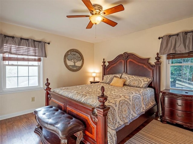 bedroom with multiple windows, wood finished floors, a ceiling fan, and baseboards