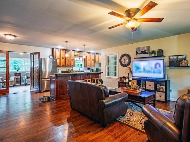 living area with a ceiling fan, dark wood finished floors, and baseboards