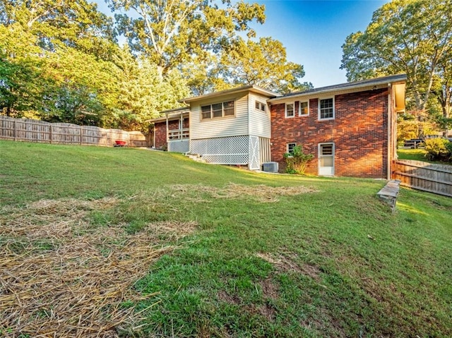 back of house with brick siding, a lawn, cooling unit, and fence