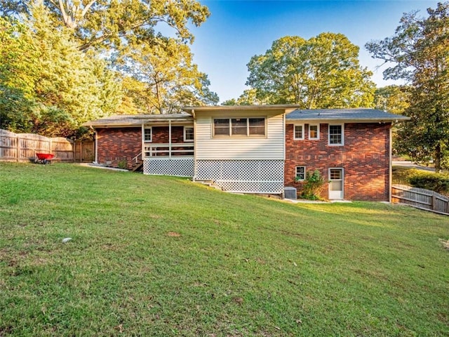 back of house featuring a yard, brick siding, and fence