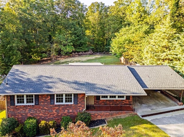 view of front of property with brick siding, a shingled roof, an attached carport, driveway, and a front lawn