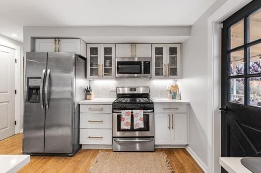 kitchen with decorative backsplash, stainless steel appliances, light hardwood / wood-style flooring, and gray cabinetry