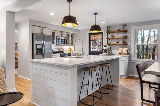 kitchen featuring an island with sink, light hardwood / wood-style floors, pendant lighting, white cabinets, and appliances with stainless steel finishes