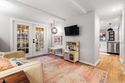 living room with french doors, light hardwood / wood-style floors, and beam ceiling