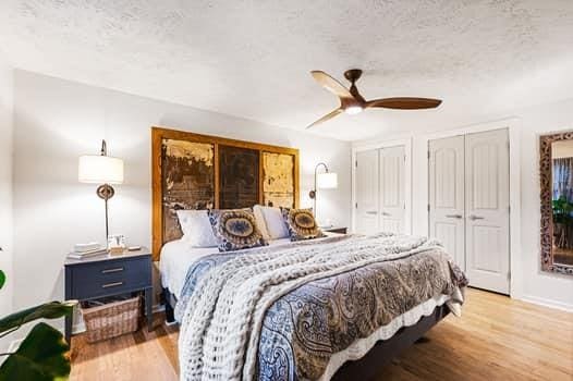 bedroom featuring ceiling fan, light hardwood / wood-style floors, and multiple closets