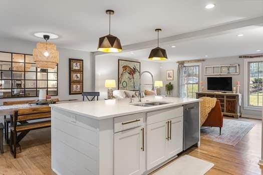 kitchen with dishwasher, white cabinets, sink, hanging light fixtures, and an island with sink