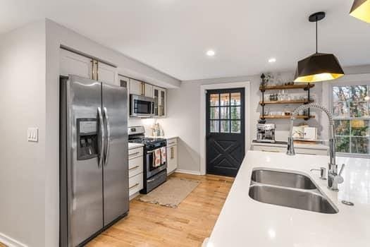 kitchen featuring sink, hanging light fixtures, appliances with stainless steel finishes, light hardwood / wood-style floors, and white cabinetry