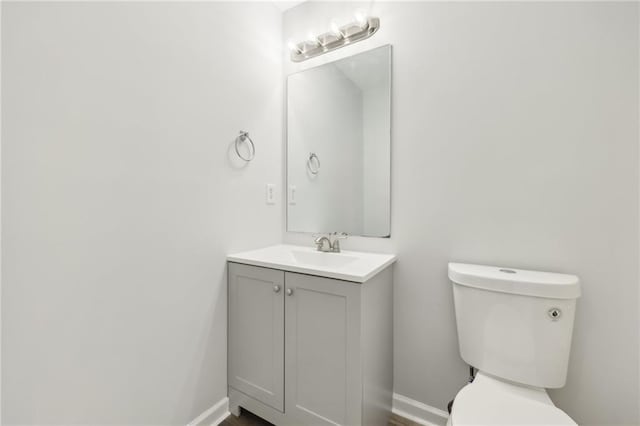 bathroom featuring baseboards, vanity, and toilet