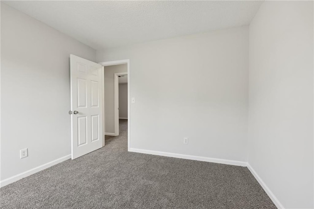 unfurnished room with a textured ceiling, carpet floors, and baseboards